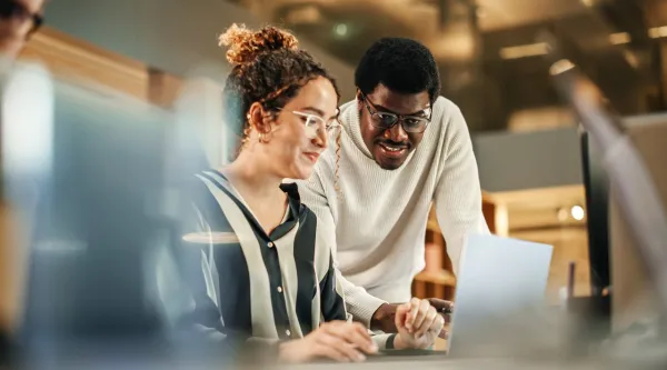 Two colleagues looking at a laptop