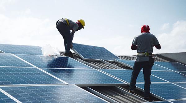 Zwei Männer legen Solarzellen aufs Dach