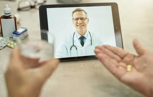 Person taking medication while speaking to their doctor via video call 