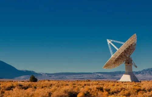A large radio telescope dish stands in a dry desert