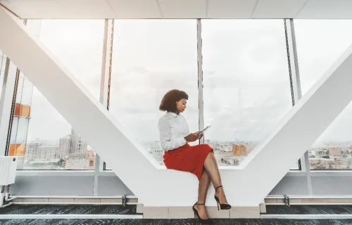 Femme assise dans un espace de travail moderne, utilisant une tablette