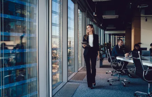 Responsable administrative en tenue formelle marchant dans un bureau avec une tablette…
