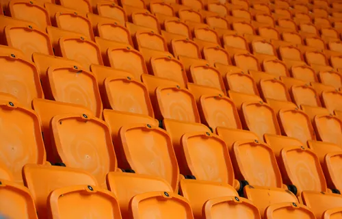 Rows of vacant orange fold down seats at a sports stadium