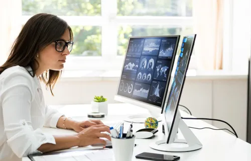Analyst woman reviewing data on monitors