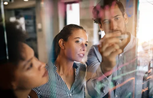 three people looking at a whiteboard