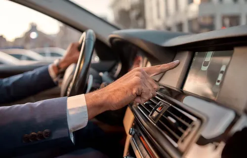 La main de la personne atteignant l’écran sur le tableau de bord de la voiture