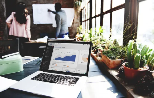 A laptop on a table displaying a dashboard with charts.
