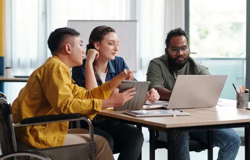 Three people working together, looking at a laptop