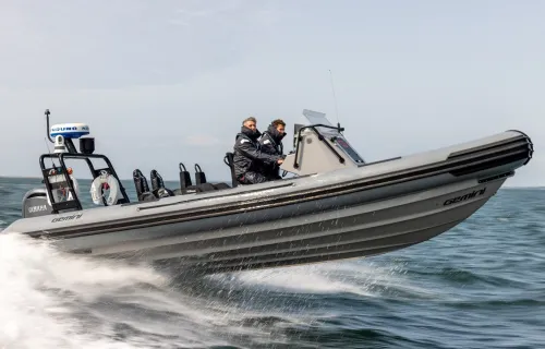 Two people ride in a rigid inflatable motorboat speeding across the water
