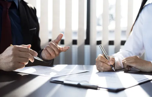 Two people signing a document around insurance.