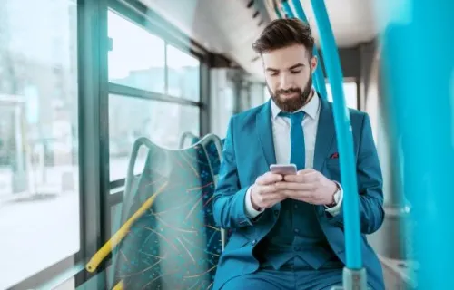 Ein junger Geschäftsmann, der im öffentlichen Bus sein Smartphone benutzt