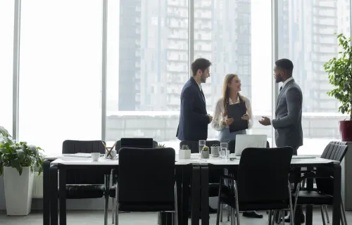 Three business people talking in front of an office window