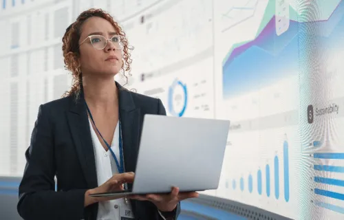 Business analyst reviewing hybrid cloud data dashboards on laptop