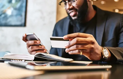 Businessman holding mobile and credit card in cafe