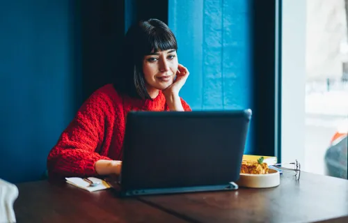 woman sitting at desk on computer in cafe