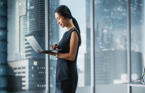 Professional standing and using a laptop