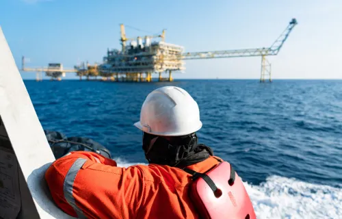 operational worker on the sea looking at an oil rig