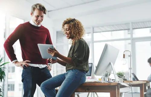 Two consultants in a modern office, collaborating and discussing AI while using a tablet