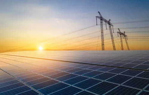 solar panels with pylons and a sunset in the background