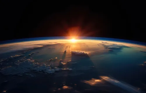 Earth’s curved horizon seen from space, with a sunrise casting light across the atmosphere