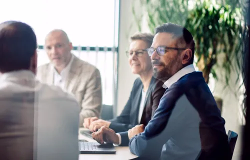A group of colleagues seated around a conference table during a business meeting