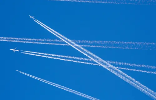 Several civilian or military aircraft safely flying at high altitude showing vapour trails