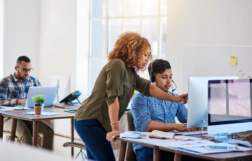 Colleagues reviewing work on a monitor at a desk