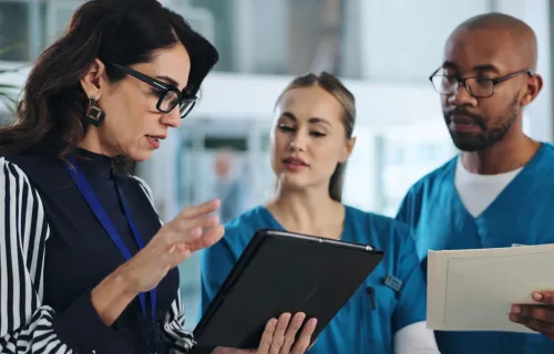 consultant discutant des données sur une tablette avec des professionnels de santé
