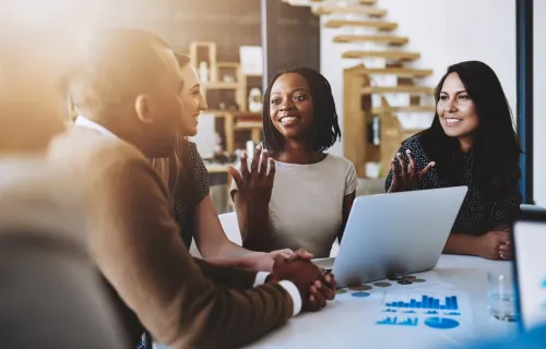 Consultants smile and discuss data on laptop