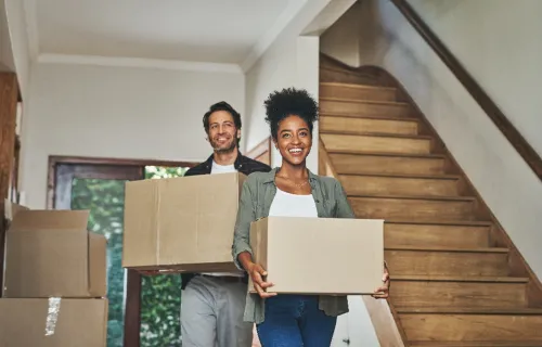 Couple carrying moving boxes into new home