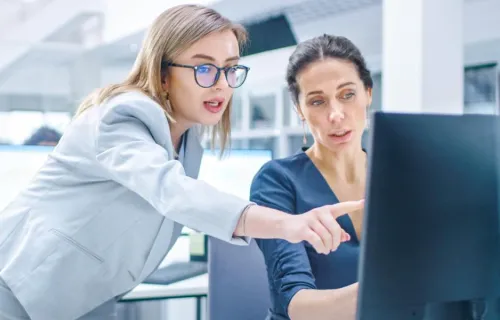 Young professional females looking at a computer screen.