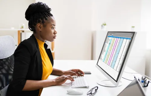Professional analyzing data on a large monitor at her desk