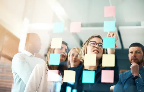 Führungsteam analysiert Change-Trigger und Wirkungsketten an einer Glaswand im Rahmen eines Change-Management-Workshops.