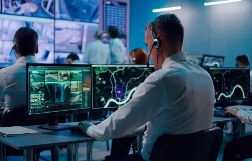 Defence consultant working at dual monitors in control room