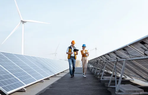 two workers walking between solar panels