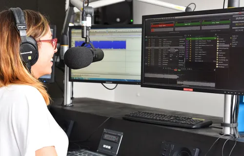 Eine Radiomitarbeiterin sitzt vor einem Bildschirm und verwendet CGI dira Onair Player