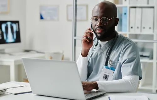 Doctor on phone looking at laptop