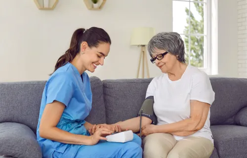 Health care professional takes patient's blood pressure reading at home