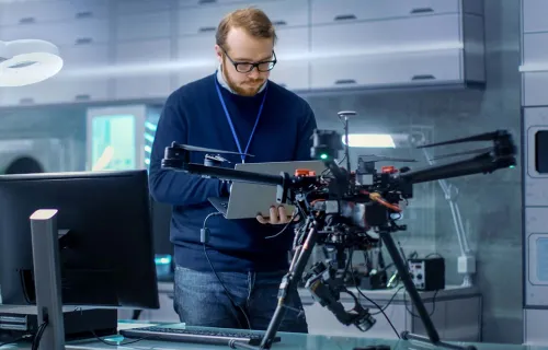 Ein Mann steht vor einer Drohne und programmiert diese
