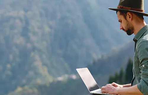 Un homme en train d'utiliser son ordinateur portable dans la nature