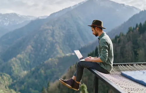 Un homme en train d'utiliser son ordinateur portable dans la nature