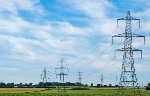 Kuva sähkölinjoista kesäisellä pellolla