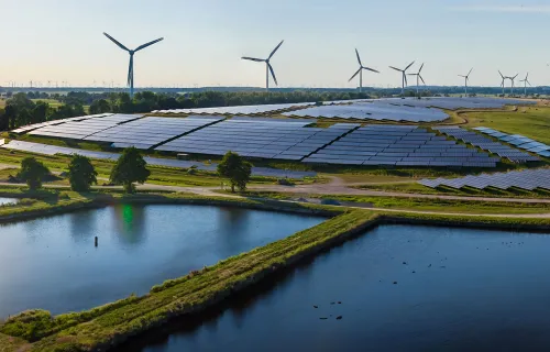 solar farm and wind turbines in a field near water