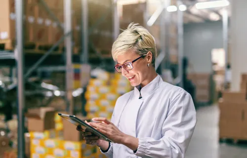 Manufacturing employee using a tablet in a warehouse