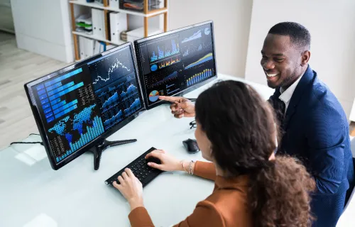 Two professionals collaborating at a workstation with two monitor