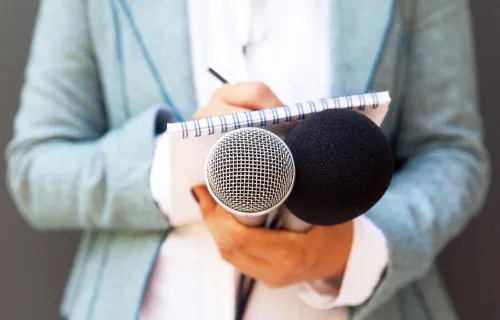 Journaliste tenant un microphone et écrivant sur un bloc-notes lors d'une conférence de presse
