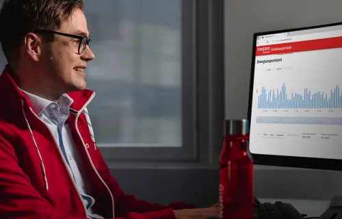 Junger Mann mit roter Jacke sitzt vor einem Bildschirm und schaut sich ein Diagramm an