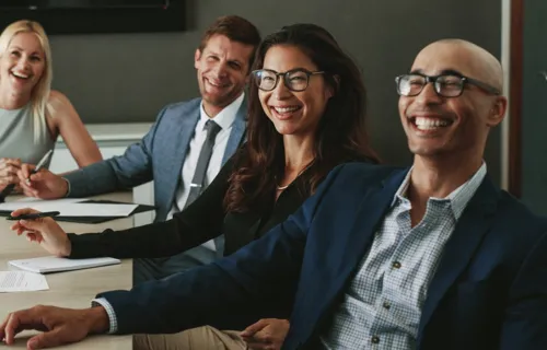 Four business people smiling while listening to a speaker