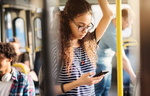 Junges Mädchen steht im Bus und überprüft Nachrichten auf ihrem Handy 
