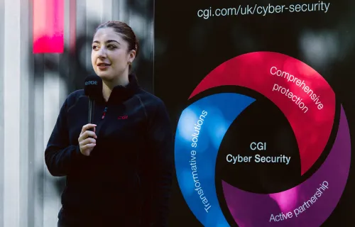 Graduate doing interview in front of CGI Cyber Escape escape room